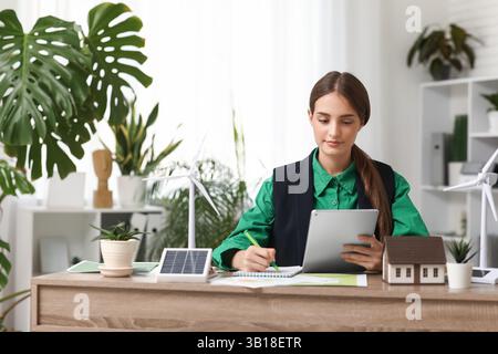 Weibliche Ingenieurin, die mit Tablet-Computern und Windturbinenmodellen am Tisch im Büro arbeitet Stockfoto