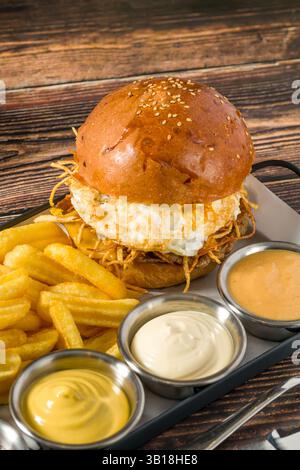 Eierburger mit knusprigen Kartoffeln serviert mit Pommes und Saucen Stockfoto