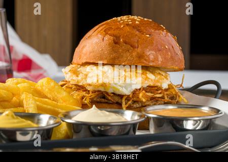 Eierburger mit knusprigen Kartoffeln serviert mit Pommes und Saucen Stockfoto