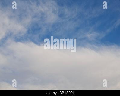 Weiße Wolken schweben sanft über einem tiefblauen Himmel und schaffen eine ruhige und friedliche Atmosphäre Stockfoto