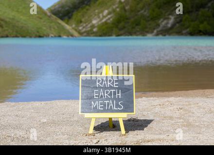 Symbol für Seltenerdmetalle. Konzeptworte seltene Metalle auf wunderschöner Tafel. Wunderschöner Bergsee im Hintergrund. Gewerbe- und Seltenerdmetalle Stockfoto