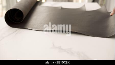 Rolle aus dunkelbraunem Leder auf weißem Marmorhintergrund Stockfoto