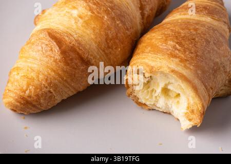 Frisch gebackene Croissants, serviert auf einem neutralen Teller, die ihre goldenen Schichten und die blättrige Textur hervorheben Stockfoto
