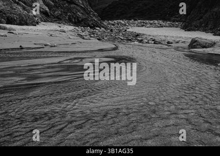 Garrapata State Park and Beach, Monterey County, Kalifornien - 23. April 2025 Wasser fließt über Sand, Felsen und Kieselsteine in den Ozean Stockfoto