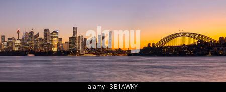 Der farbenfrohe Sonnenuntergang in der goldenen Stunde über der Skyline von Sydney am Wasser in Australien über die Hafengewässer verschwommen. Stockfoto