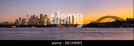 Der farbenfrohe Sonnenuntergang über der Skyline der Stadt Sydney am Wasser in Australien über die Hafengewässer verschwimmerte. Stockfoto