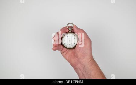 Kaukasischer männlicher Hand mit antiker Eisenbahnleiteruhr auf weißem Hintergrund Stockfoto