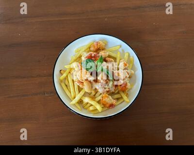 Mozarella Chicken Barbeque serviert mit Pommes Frites auf einer weißen Schüssel, die von einem Holztisch isoliert ist Stockfoto