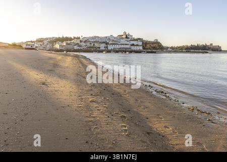 Sonnenaufgang am Atlantik, Skyline eines Fischerdorfes hinter einem Hafen. Sandstrand bei Sonnenaufgang. Landschaftsfotografie in Ferragudo, Portimao, Algar Stockfoto