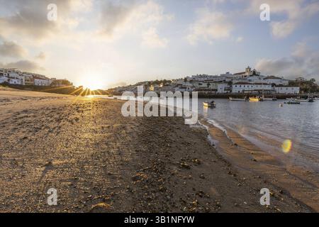 Sonnenaufgang am Atlantik, Skyline eines Fischerdorfes hinter einem Hafen. Sandstrand bei Sonnenaufgang. Landschaftsfotografie in Ferragudo, Portimao, Algar Stockfoto