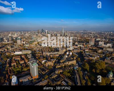 Pulsierende Luftaufnahme von Londons grünen Wohngebieten im goldenen Herbstlicht, das in das berühmte Finanzviertel mit dem Shard Tower fließt. Stockfoto