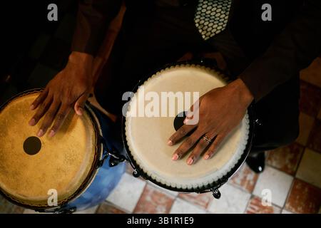 Blick von oben auf männliche Musiker, die rhythmischen Beat auf traditionellen Conga-Trommeln erzeugen, während sie afro-kubanische Jazzmusik mit einer Band in der Bar spielen Stockfoto