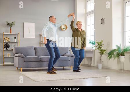 Glückliches Seniorenpaar, das zu Hause tanzt, ältere sorglose aktive Leute, die Spaß machen, genießen die gemeinsame Zeit Stockfoto