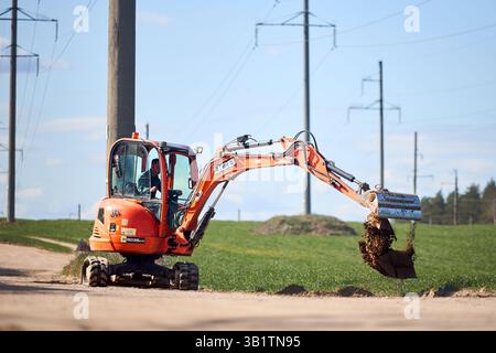 Mir, Weißrussland - 7. April 2025: JCB 8035 ZTS Minibagger mit Arbeiter im Grabboden auf dem Feld. Graben für Kabel oder Rohrleitungen. Stockfoto