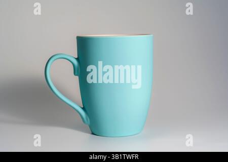 Minimalistischer weißer Becher gefüllt mit schwarzem Kaffee, platziert auf einer hellen Oberfläche mit einem definierten weichen Schatten und neutralem Hintergrund. Stockfoto