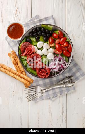 Pizza Salat wirft eine Mischung aus Salat, Würstchen, Mozzarella, schwarzen Oliven und roten Zwiebeln in einer frischen, geriebenen Tomaten Vinaigrette in der Nähe auf dem Teller auf dem Stockfoto