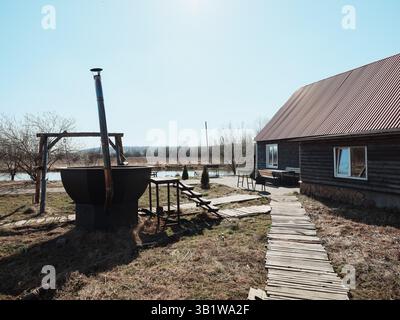 Eine malerische rustikale Landszene mit einem traditionellen Brunnen und einem charmanten Haus in der Nähe Stockfoto