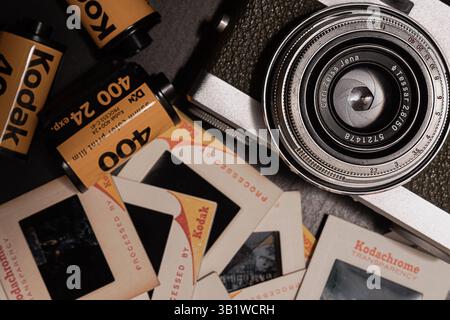Die 35-mm-Vintage-Filmkamera mit Carl Zeiss ® Objektiv und Kodak ® Filmkanaster sowie 35-mm-Kodachrome-Kamera lässt sich auf dunklem Hintergrund umdrehen Stockfoto
