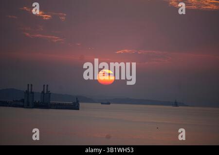 Sonnenuntergang über dem Meer mit Schiffen und Hafensilhouetten am Horizont. Salou, Spanien Stockfoto