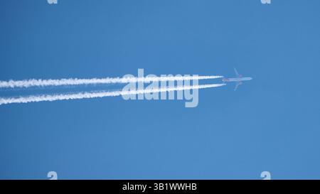 Das Flugzeug fliegt hoch am Himmel mit Kondensstreifen Stockfoto