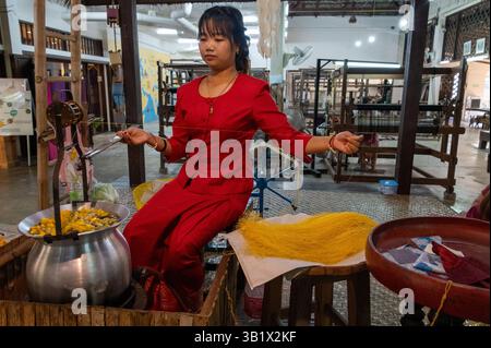 Nach dem Kochen werden die lockeren Rohseidenfasern ordentlich zu kegelförmigen Garnen gefaltet und dann im „Thai Silk Village“ in Ban zu Garnen versponnen Stockfoto