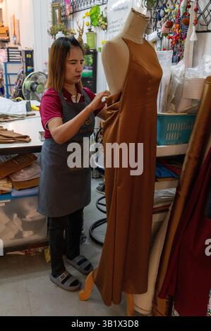 Eine Seemännerin, die in der Schneiderabteilung des „Thai Silk Village“ in Ban Sanuan NOK, einer Ville, die die letzten Anpassungen an einem Seidenkleid vorgenommen hat Stockfoto