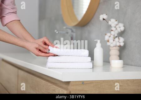Frau, die sauberes Handtuch vom Waschtisch im Bad nimmt, Nahaufnahme Stockfoto