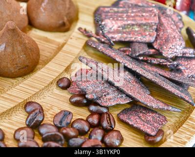 Köstliche Schokoladen-Leckereien und geröstete Kaffeebohnen auf einer Holzplatte für ein einladendes Desserterlebnis Stockfoto