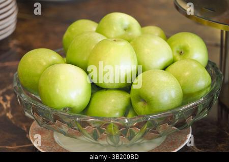 Frische grüne Äpfel in einer Kristallschale auf einer Arbeitsplatte angeordnet Stockfoto