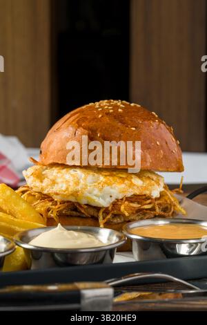 Eierburger mit knusprigen Kartoffeln serviert mit Pommes und Saucen Stockfoto