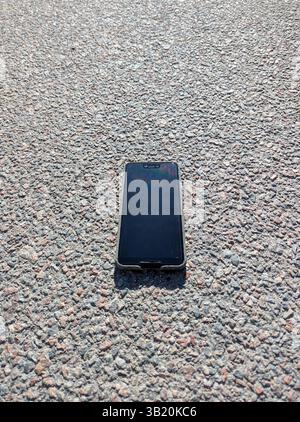 Das Smartphone liegt auf dem Asphalt Stockfoto
