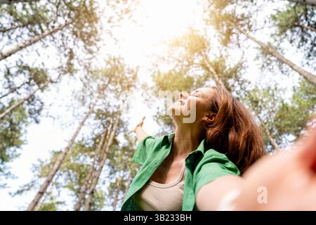 Eine freudige Frau, die im Wald ein Selfie macht Stockfoto