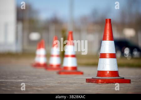 Reihe rot-orange gestreifter Kegel auf der Straße, um Unfälle zu vermeiden. Selektiver Fokus Stadtverkehrszeichen-Konzept mit Kopierraum Stockfoto