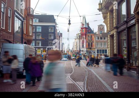 Geschäftige Straßenszene in Amsterdam mit historischer Architektur und Straßenbahnlinien Stockfoto