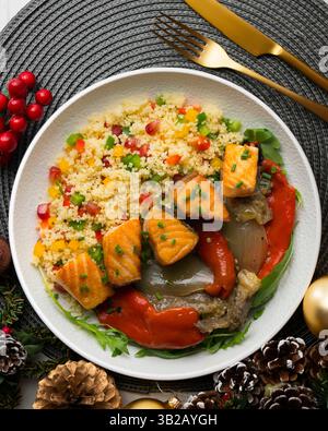 Gericht mit gebackenem Lachs, Paprika und Couscous-Salat. Tisch mit Blick von oben mit weihnachtsdekoration. Stockfoto
