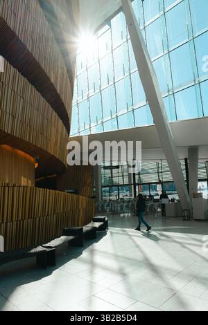 Oslo, Norwegen - 13. April 2024: Menschen, die spazieren gehen und entspannen in der Oper Oslo, Einem modernen architektonischen Gebäude mit schrägem Dach am Ufer. Stockfoto