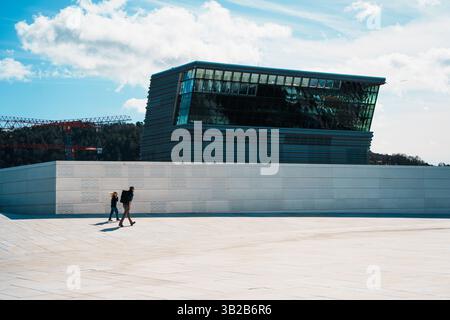 Oslo, Norwegen - 13. April 2024: Menschen, die spazieren gehen und entspannen in der Oper Oslo, Einem modernen architektonischen Gebäude mit schrägem Dach am Ufer. Stockfoto