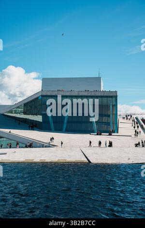 Oslo, Norwegen - 13. April 2024: Menschen, die spazieren gehen und entspannen in der Oper Oslo, Einem modernen architektonischen Gebäude mit schrägem Dach am Ufer. Stockfoto