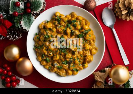 Kichererbsencurry mit Auberginen und Gemüse. Tisch mit Blick von oben mit weihnachtsdekoration. Stockfoto