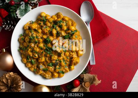 Kichererbsencurry mit Auberginen und Gemüse. Tisch mit Blick von oben mit weihnachtsdekoration. Stockfoto