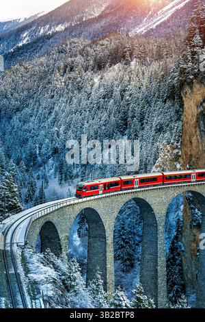 Luftaufnahme des Zuges durch den berühmten Berg in Filisur, Schweiz. Landwasser Viadukt Weltkulturerbe mit Zug Express in Schweizer Alpen Schnee Stockfoto