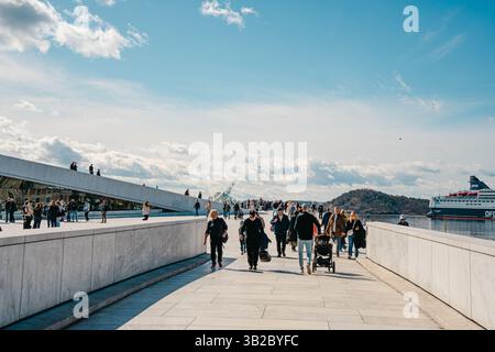 Oslo, Norwegen - 13. April 2024: Menschen, die spazieren gehen und entspannen in der Oper Oslo, Einem modernen architektonischen Gebäude mit schrägem Dach am Ufer. Stockfoto