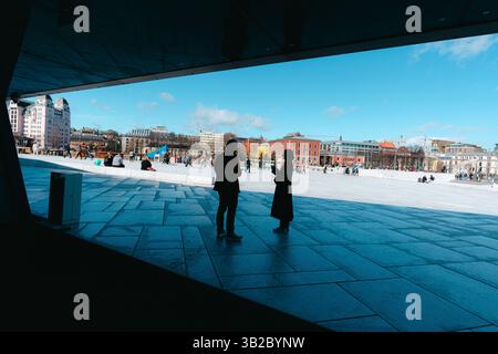 Oslo, Norwegen - 13. April 2024: Menschen, die spazieren gehen und entspannen in der Oper Oslo, Einem modernen architektonischen Gebäude mit schrägem Dach am Ufer. Stockfoto