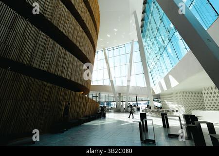 Oslo, Norwegen - 13. April 2024: Menschen, die spazieren gehen und entspannen in der Oper Oslo, Einem modernen architektonischen Gebäude mit schrägem Dach am Ufer. Stockfoto