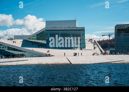 Oslo, Norwegen - 13. April 2024: Menschen, die spazieren gehen und entspannen in der Oper Oslo, Einem modernen architektonischen Gebäude mit schrägem Dach am Ufer. Stockfoto