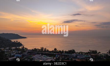 Ein atemberaubender Blick aus der Luft auf den Kata Beach in Phuket, Thailand, während des Sonnenuntergangs. Das Bild zeigt die Küste, kleine Inseln und üppig grüne hil Stockfoto
