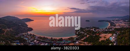 Ein atemberaubender Blick aus der Luft auf den Kata Beach in Phuket, Thailand, während des Sonnenuntergangs. Das Bild zeigt die Küste, kleine Inseln und üppig grüne hil Stockfoto