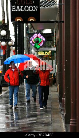 4. Dezember 2009 - Tampa, Florida, USA - TP 315622 cerr Rain (12/04/2009 Tampa) (von links) Susan und Scott Wilfong (cq), aus Charlotte, N.C., und Kaye Lockwood (cq) aus Conway, S.C., suchen nach einer Bar, in der man sich während des Regens am 7. Ave. In Ybor City am Freitag unterbringen kann. Die Fans der Clemson University trafen gestern im Raymond James Stadium zum Spiel der Atlantic Coast Conference Championship zwischen Clemson und dem Georgia Institute of Technology in ihren Wohnmobilen ein. „Wir haben das Gefühl, dass wir den Heimvorteil mit dem Regen haben“, sagte Clemson-Fan Yvette Green (cq-not Pictured) von Myrtle Beach, S.C., die trainiert Stockfoto