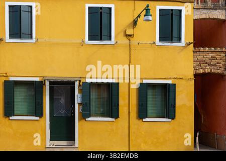Gelbe Fassade mit grünen Fensterläden und Tür Stockfoto
