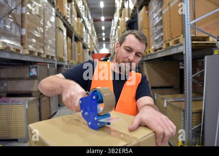 Arbeiter in einem Warenlager im Einzelhandel verpackten ein Paket mit Klebeband Stockfoto